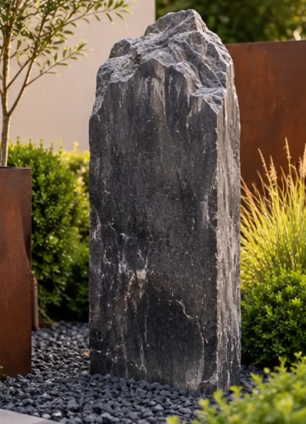 Gedenkstein aus dunklem, rau gebrochenem Naturstein vor Cortenstahl